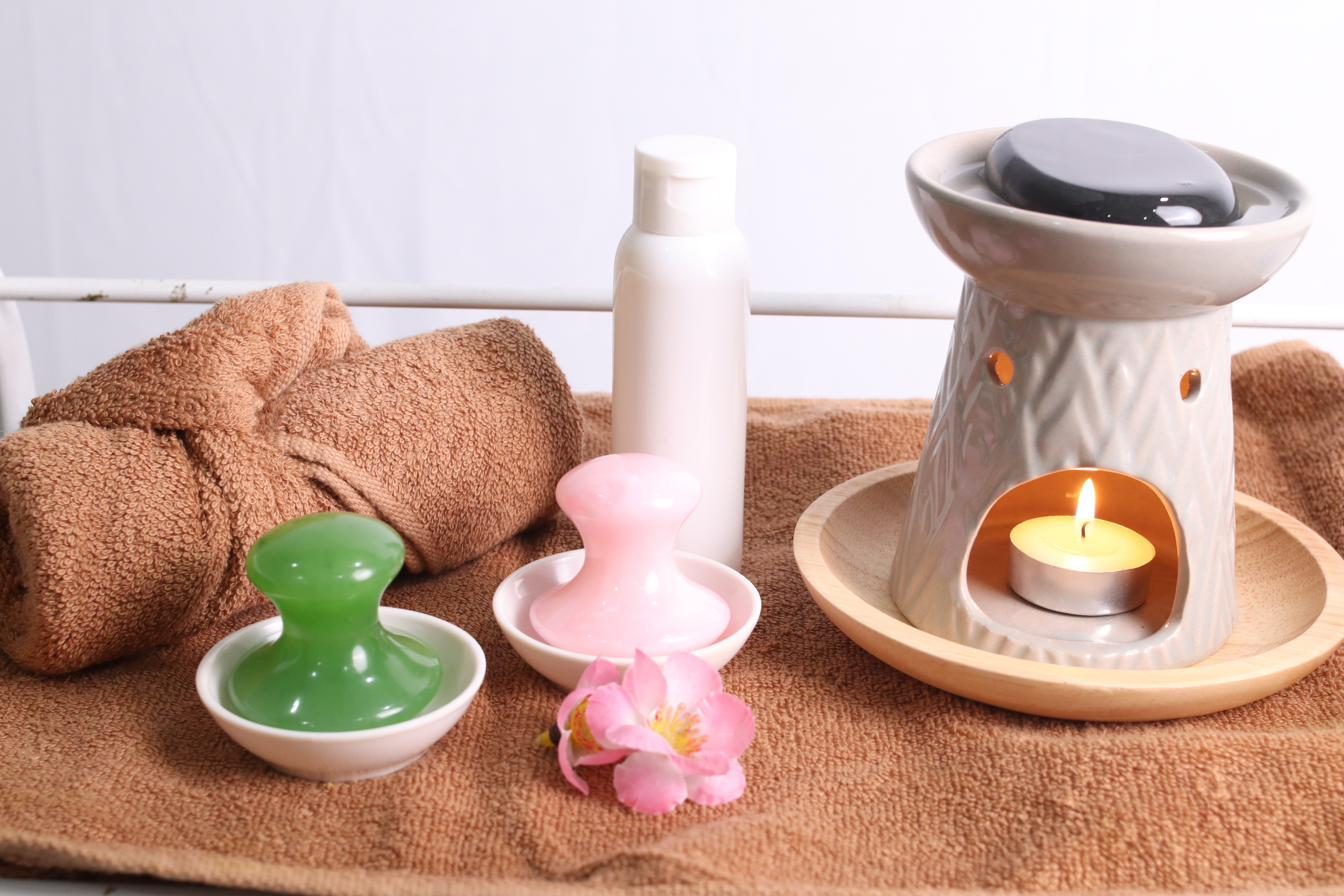 Perlengkapan perawatan spa rumahan Glamku: handuk, gua sha, dan lilin aromaterapi